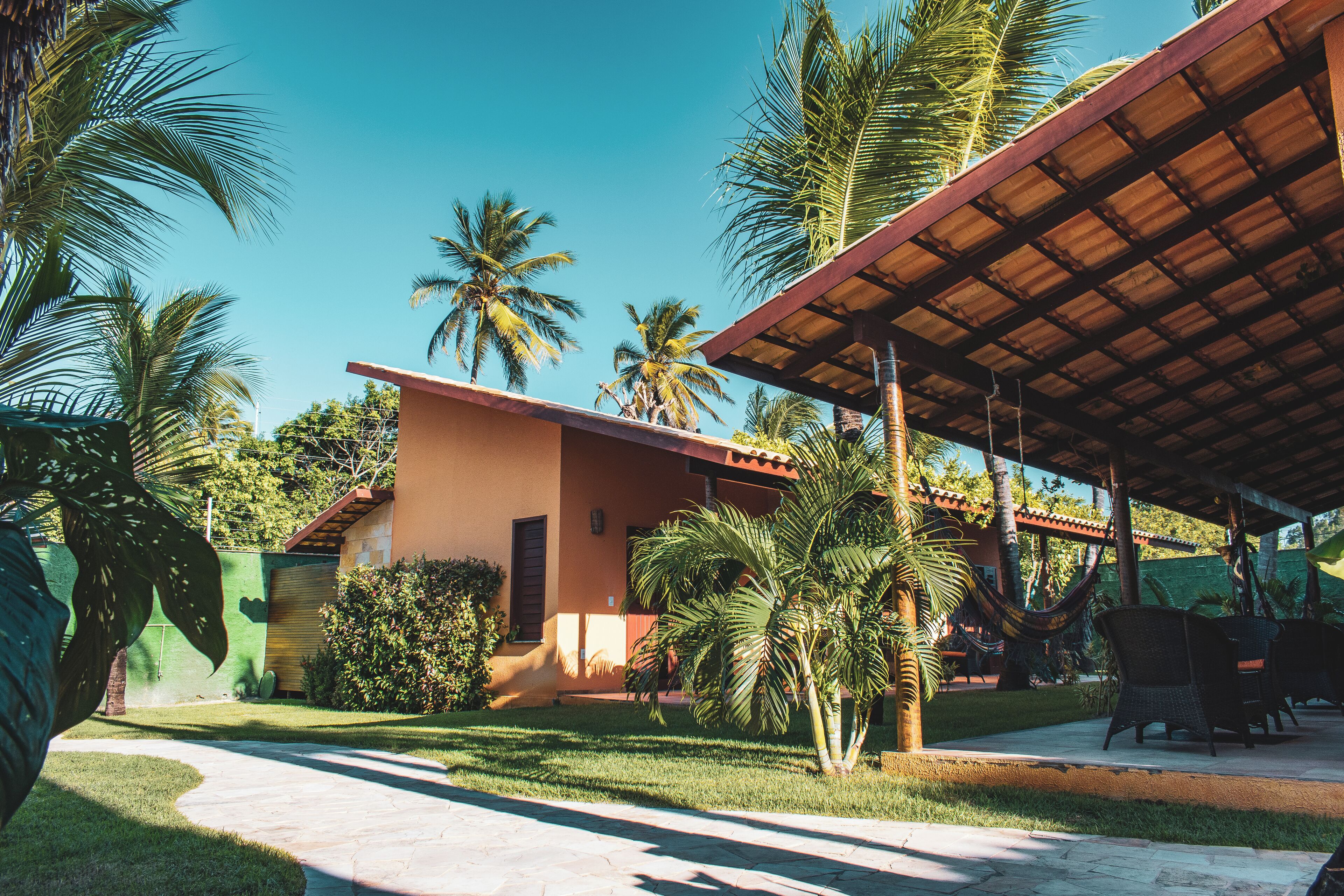 Un espacio al aire libre techado con patio, palmeras y un edificio de techo rojo.