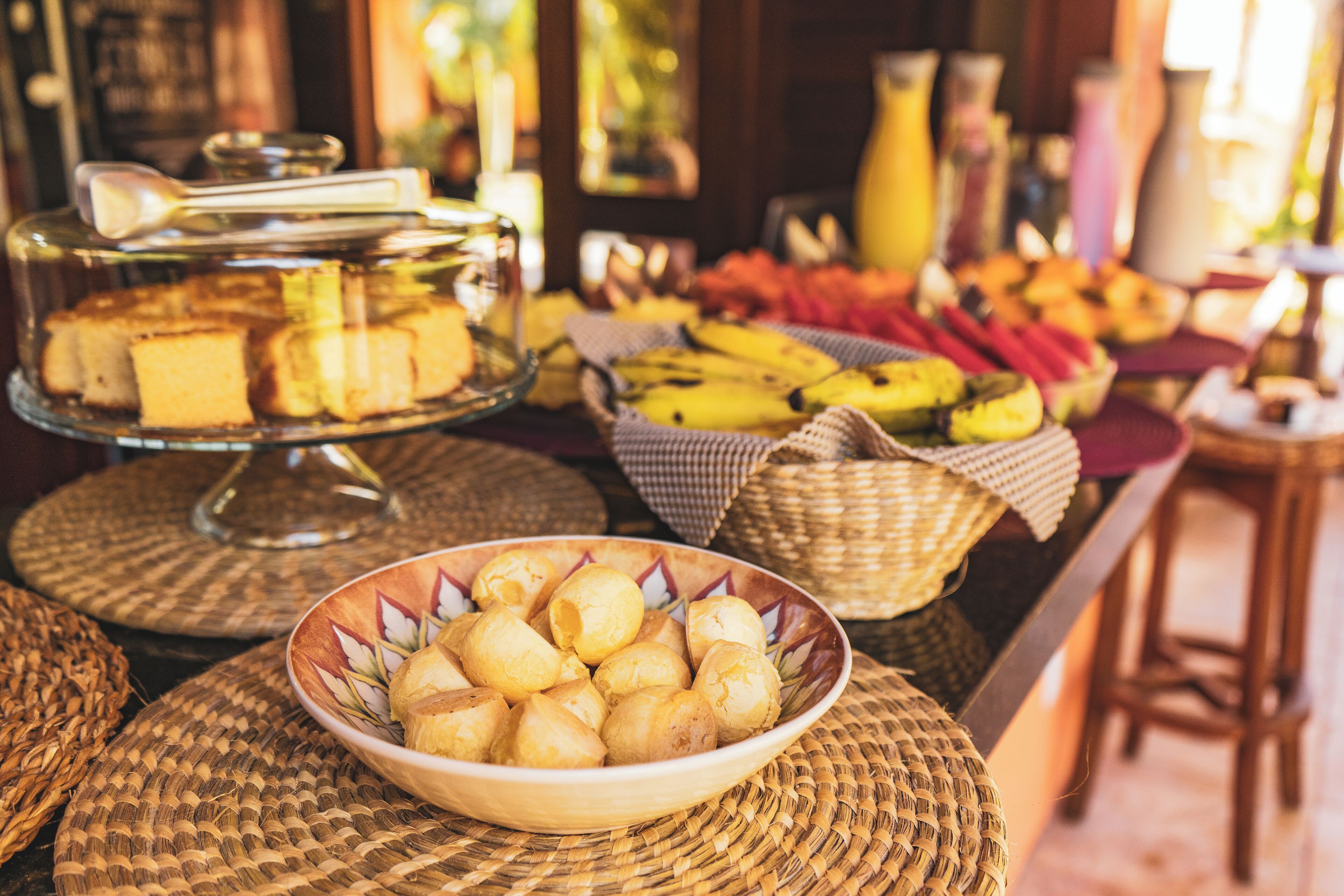 A buffet with various food items, including bread, fruits, and a bowl of pastries.