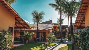 A courtyard with a hammock, palm trees, and a stone pathway. - Pousada Cumbuco Meeting Point (Caucaia)