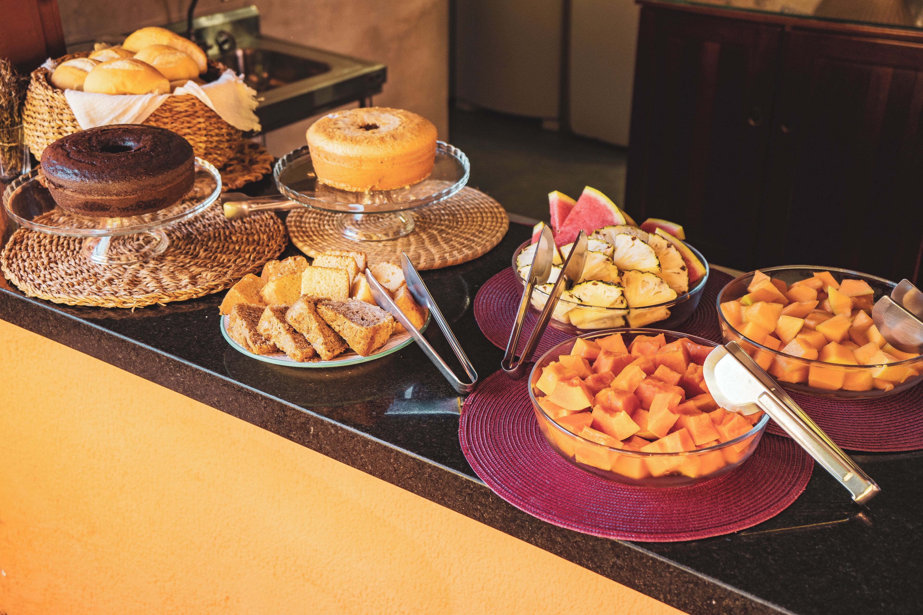 A buffet with various food items including bread, cakes, and fruit.