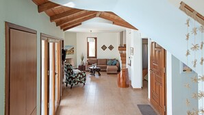Un vaste espace de vie doté d’un plafond haut, de poutres apparentes, d’un ensemble de canapés, d’une table basse et d’un escalier.