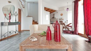 Un salon spacieux avec une table basse en bois, un canapé et un coin repas à l’arrière-plan.