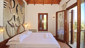 Une chambre avec un grand lit, un plafond en bois, une grande fenêtre et une peinture murale.