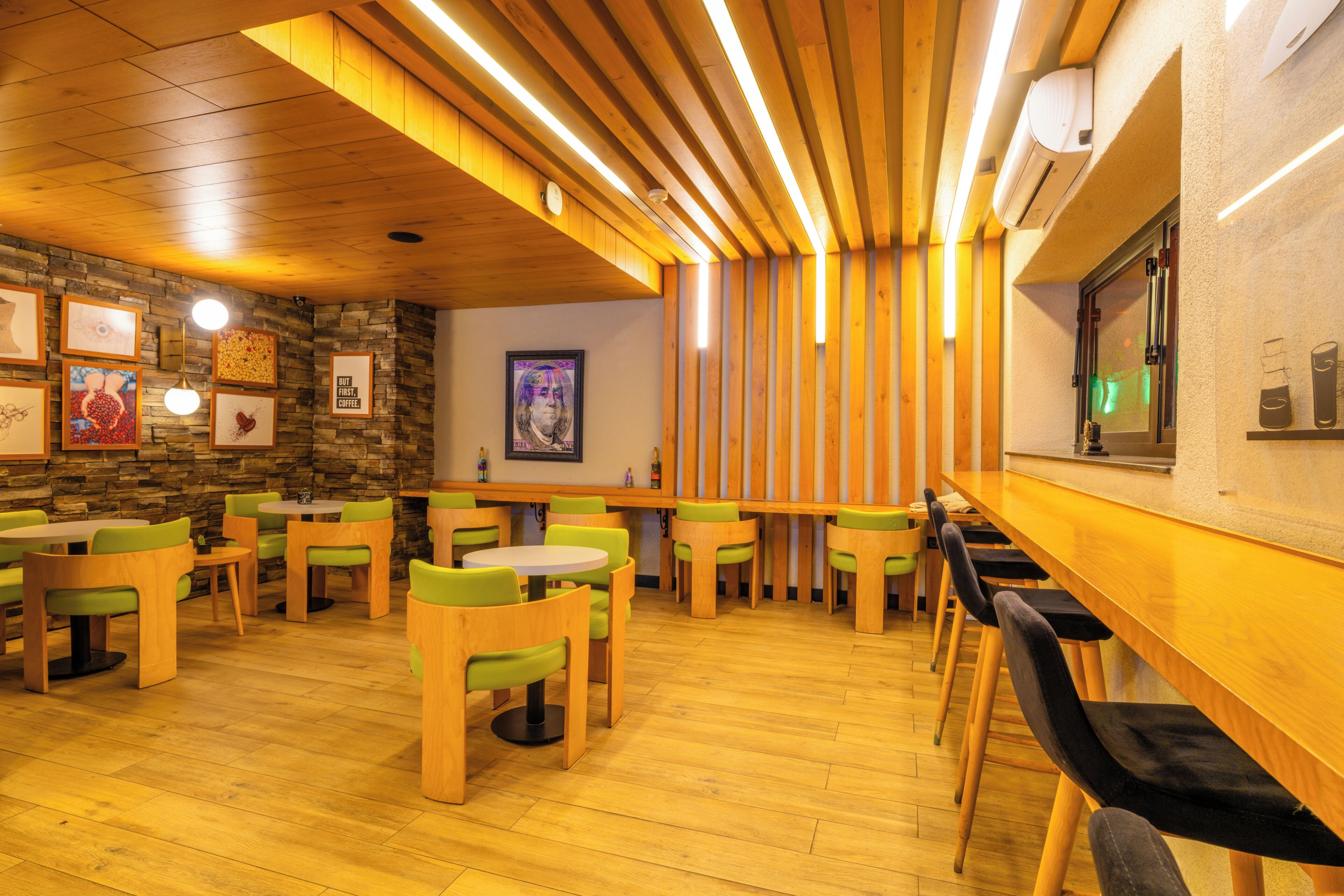 A restaurant with wooden tables and chairs, a stone wall, and a bar area.
