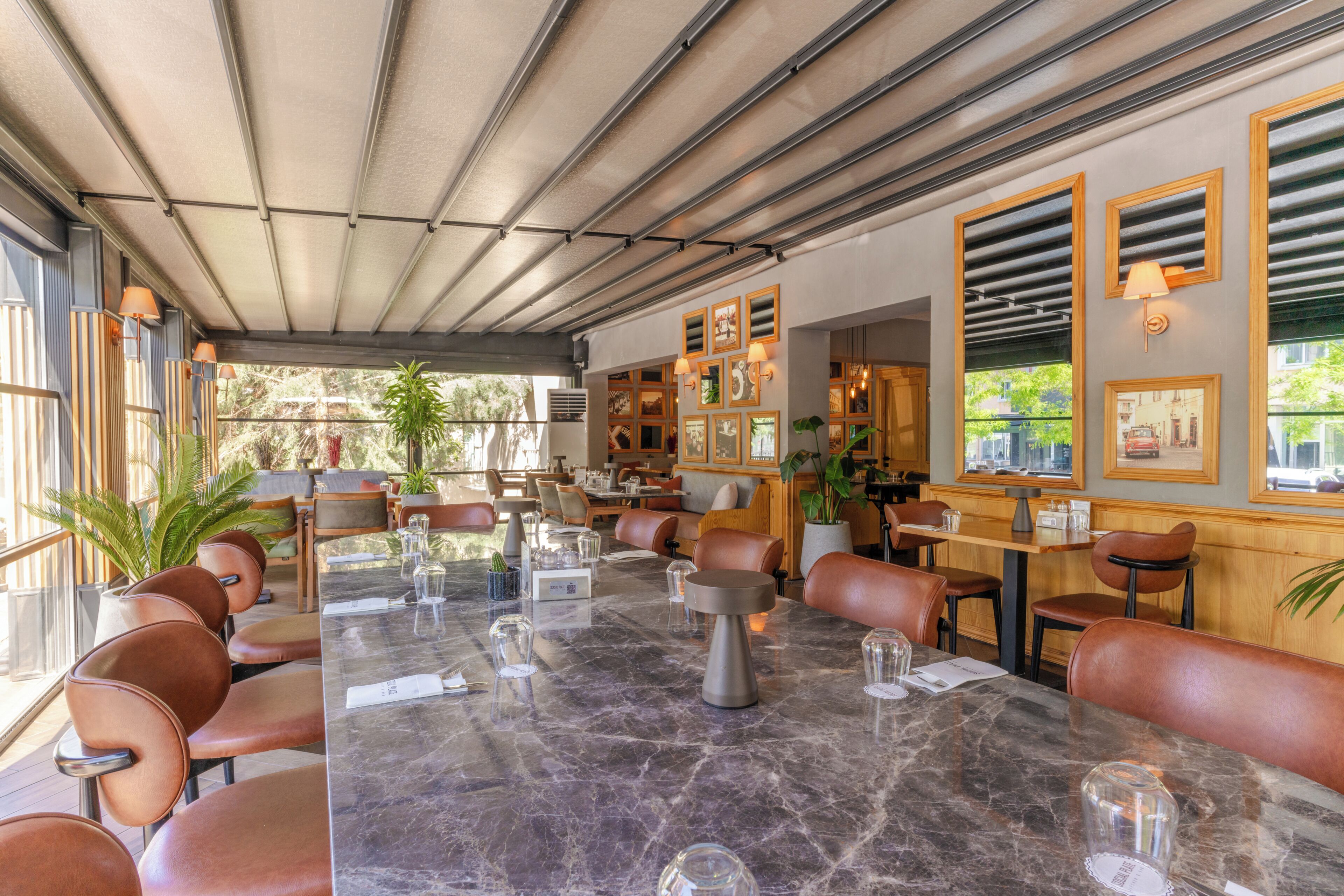 Restaurante com mesa de mármore, cadeiras de couro e quadros nas paredes.