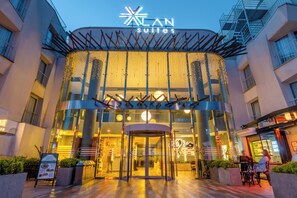 L’entrée d’un hôtel, avec une porte tournante, une enseigne indiquant « LAN Suites » et une façade en verre.