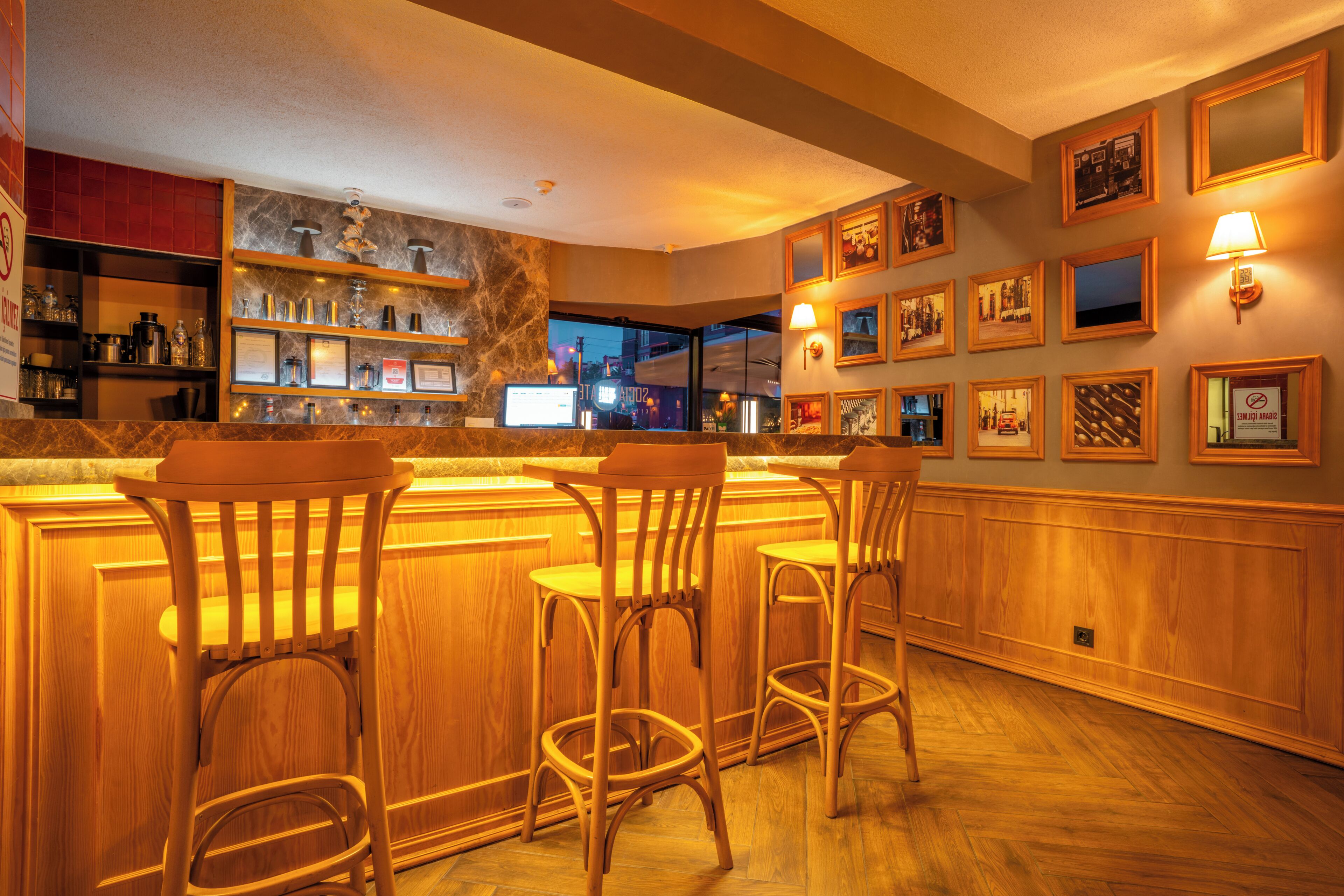 A bar area with wooden bar stools, a marble countertop, and framed pictures on the wall.