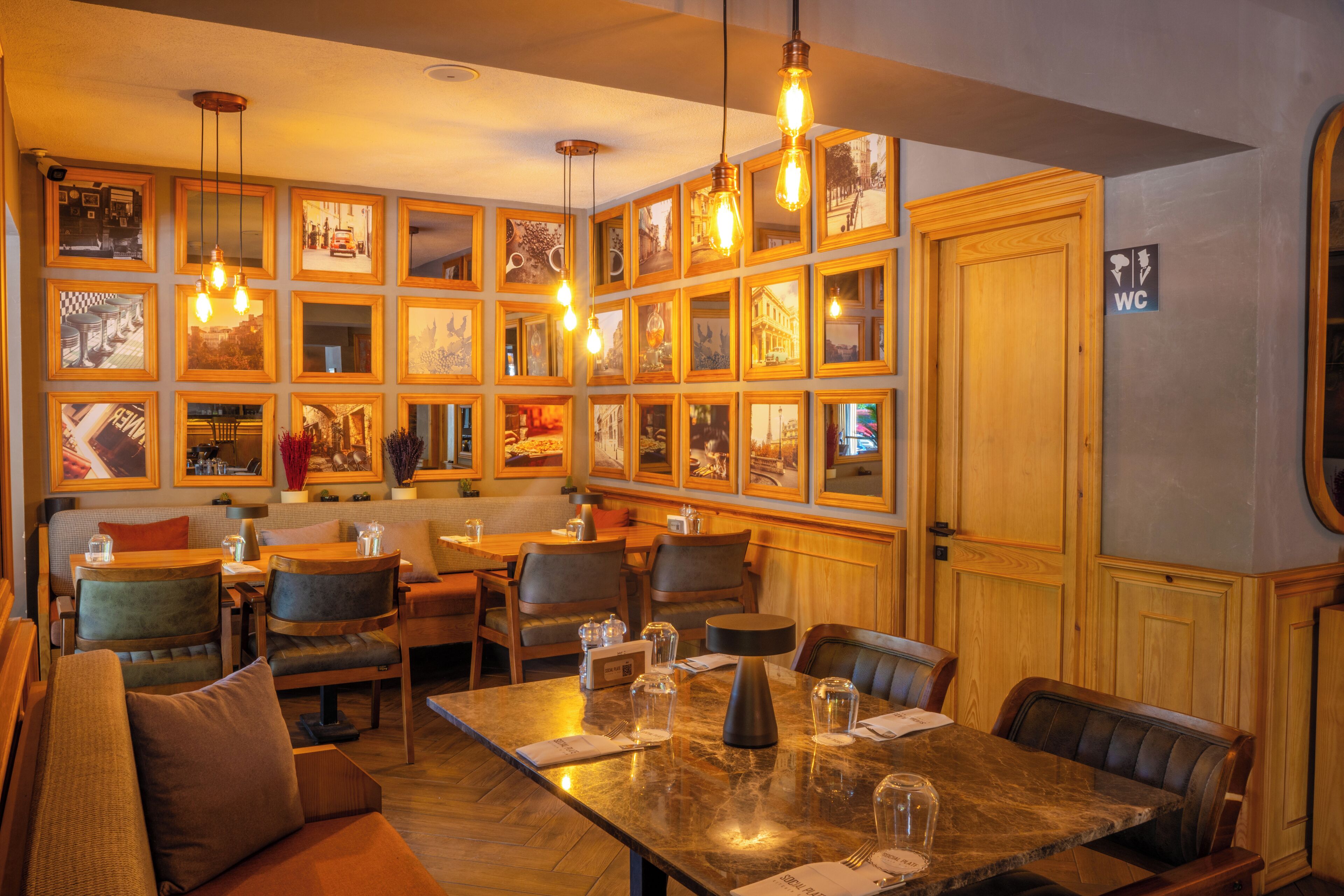 A restaurant with a long communal table, booths, and framed pictures on the walls.
