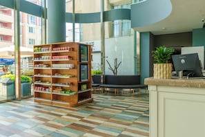 A reception area with a check-in counter, a wooden bookshelf, seating, and a large window.