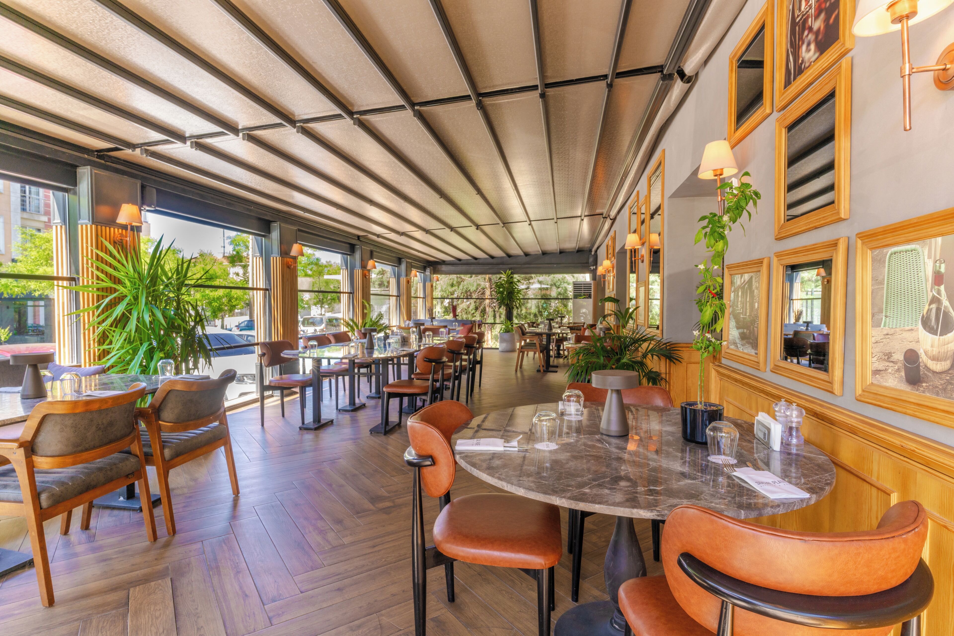 A restaurant with wooden chairs, a marble table, and potted plants.