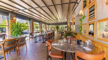 A restaurant with wooden chairs, a marble table, and potted plants.