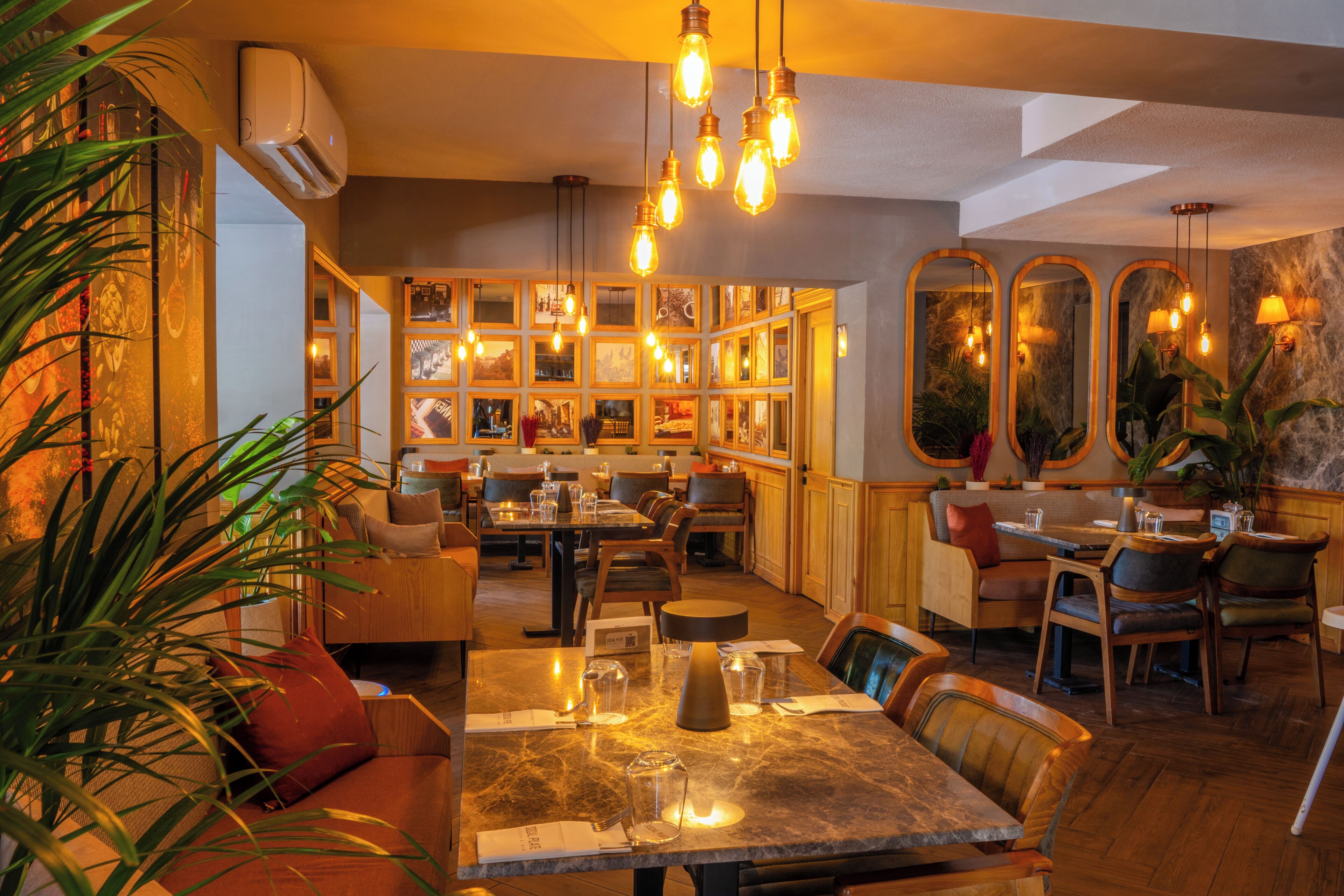 A restaurant with multiple dining tables, chairs, and hanging light fixtures.