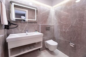 Une salle de bain moderne avec un lavabo blanc, un miroir et des toilettes.