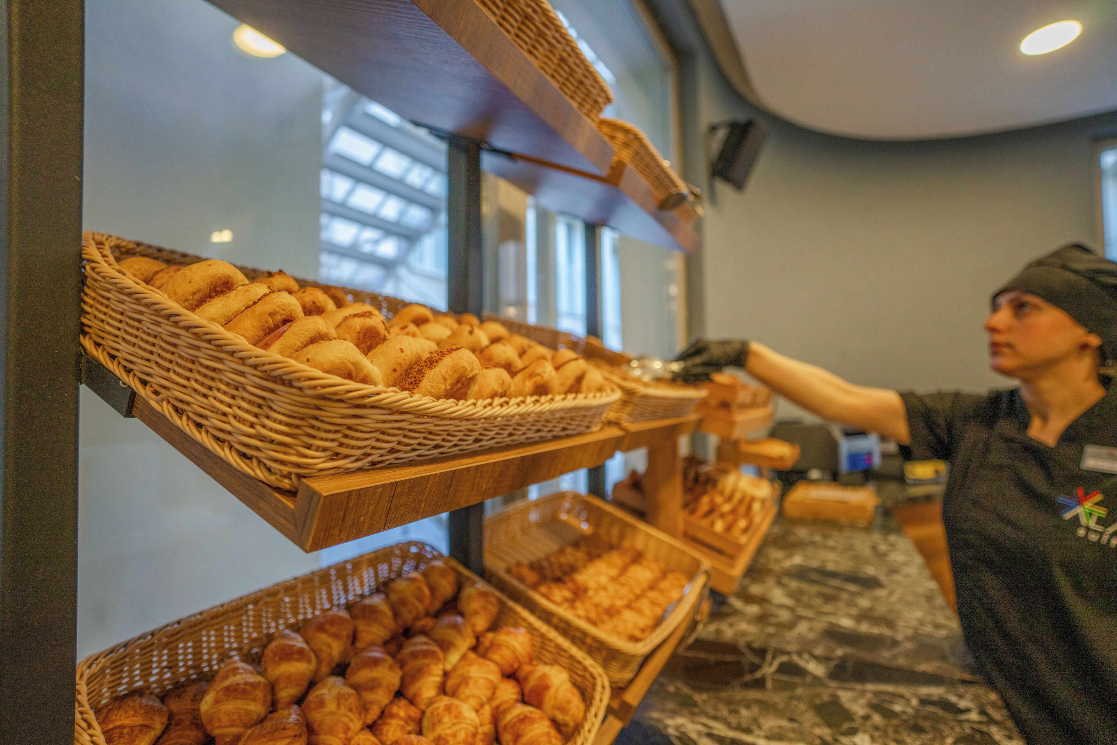 Mostrador de pastelería con cestas de productos de repostería y una persona atendiendo.