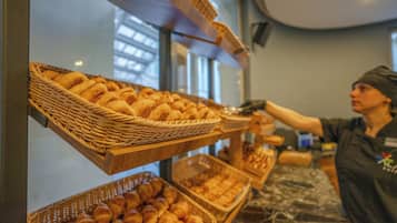 Mostrador de pastelería con cestas de productos de repostería y una persona atendiendo.