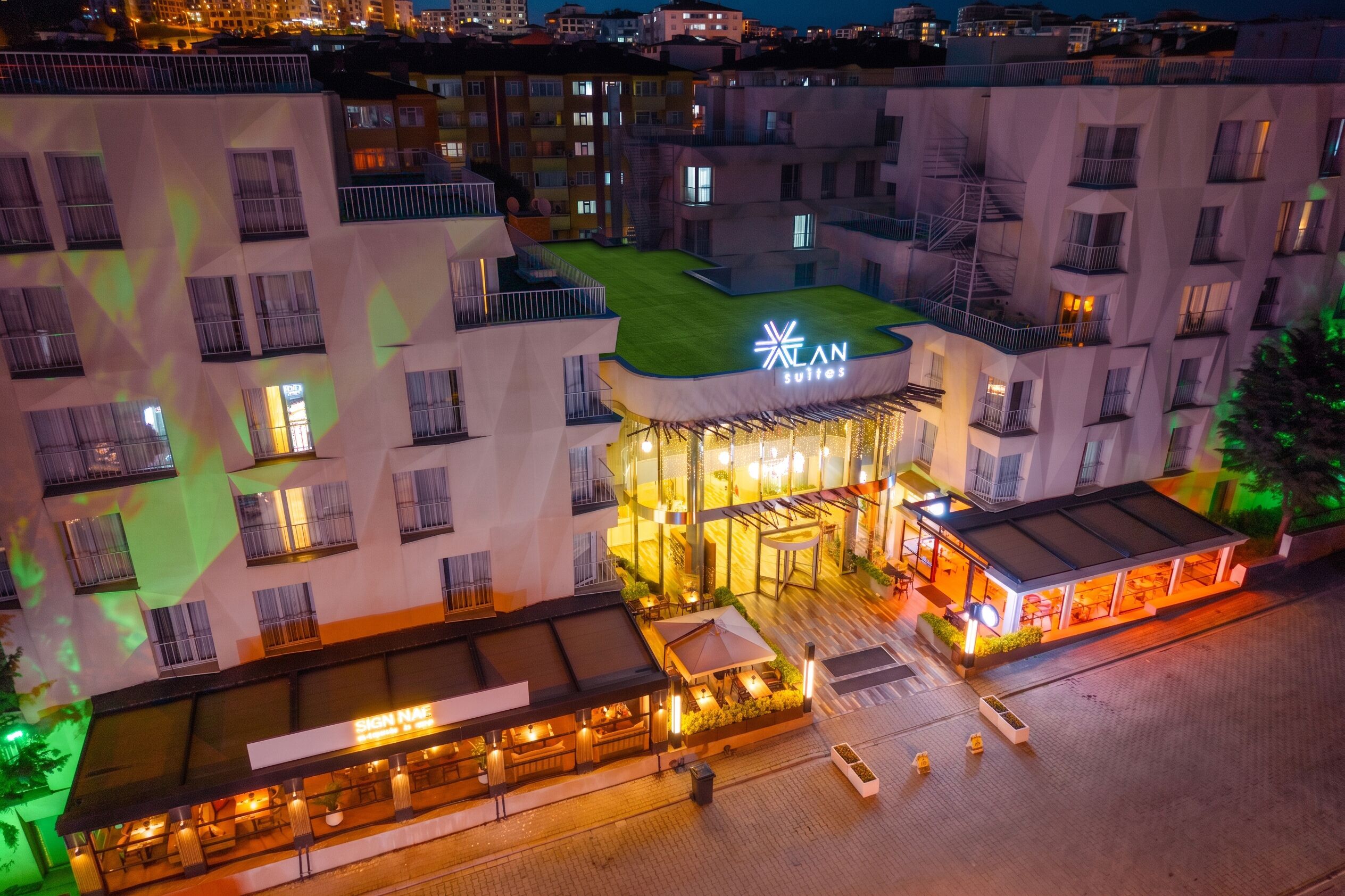 Un hotel con terraza en la azotea, un letrero que dice 'AN Suites' y un restaurante llamado 'SIGN N'FLE'.