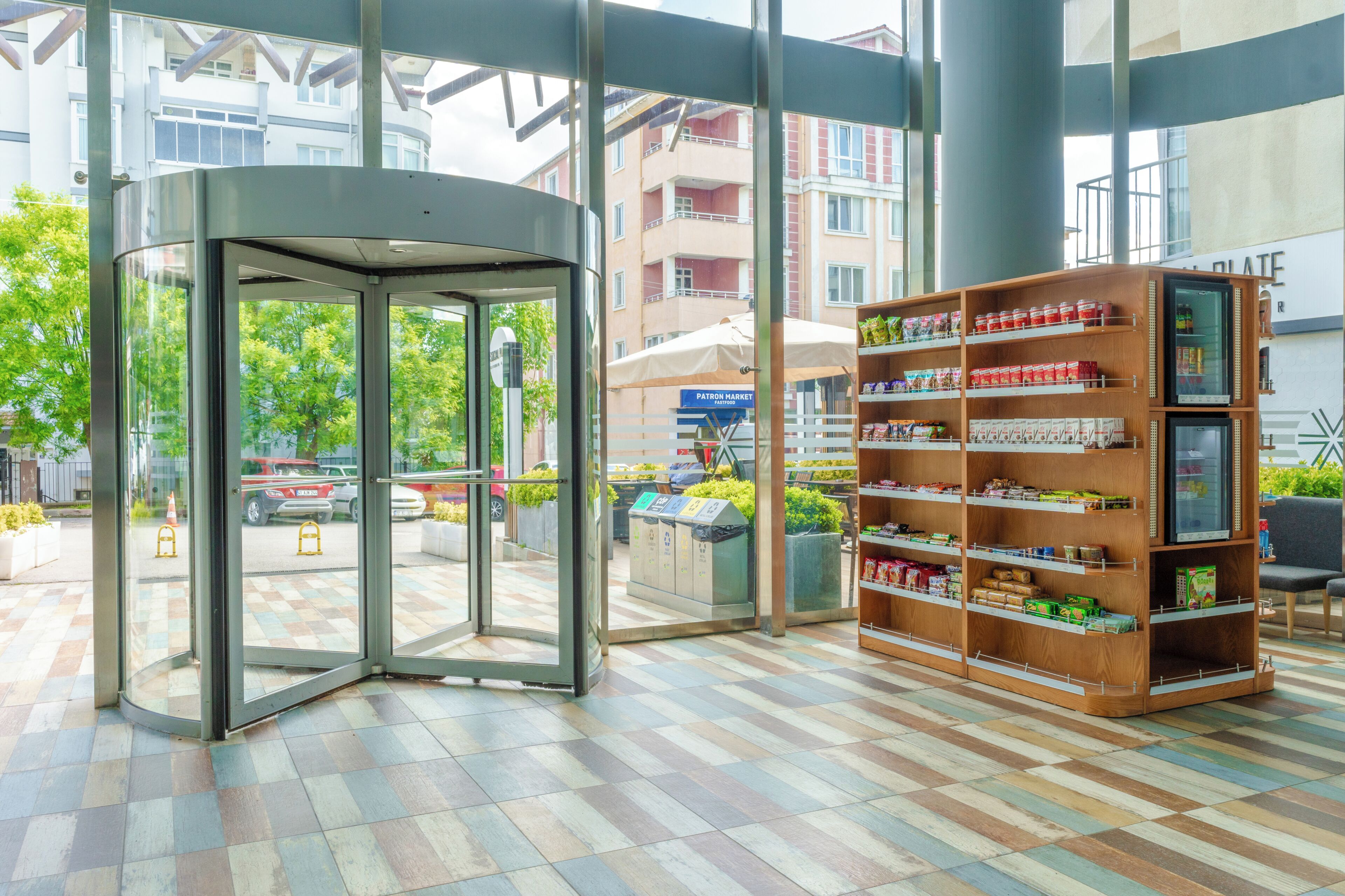 A revolving door entrance, a vending machine, and a wooden shelf with snacks.
