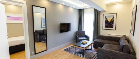 A modern living room with a sofa, armchair, coffee table, and a flat-screen TV.