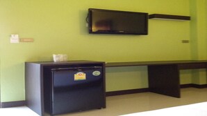 A room with a small black refrigerator, a flat-screen TV mounted on the wall, and a desk with a chair. - The Sixnature Resort Bangsaen (Chonburi)