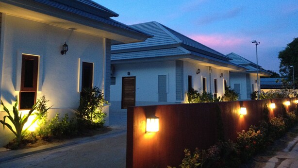 A row of modern houses with uniform architecture, a well-maintained garden, and a clear sky at dusk. - The Sixnature Resort Bangsaen (Chonburi)