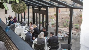 A restaurant with outdoor seating, large windows, and potted plants. - Hotel 6400 (Sønderborg)