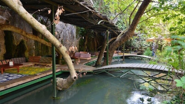 Ein naturbelassenes Innenambiente mit Wasserspiel, Holzbrücken und Sitzbereichen.