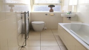 Une petite salle de bain moderne, équipée de toilettes, d’un lavabo et d’une baignoire.