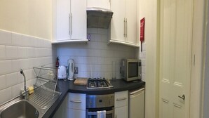 Une cuisine compacte équipée d’un évier, d’une cuisinière, d’un four à micro-ondes et d’un four traditionnel.