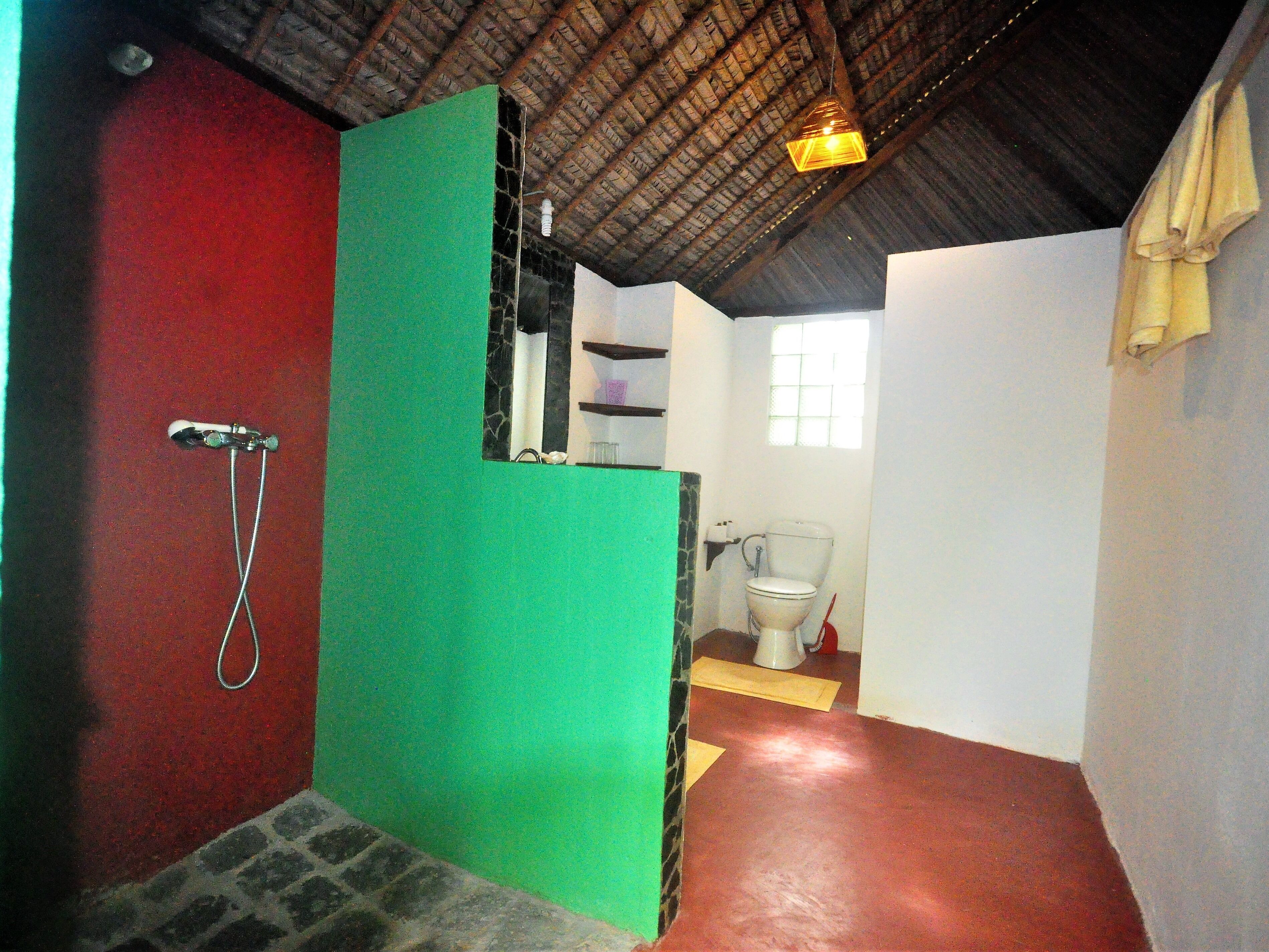 A bathroom with a shower, toilet, and a window.