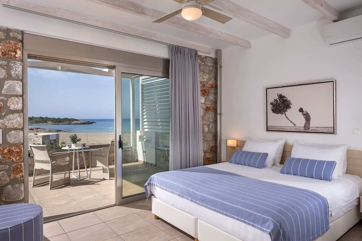 Un dormitorio con una cama grande, vistas a la playa y un ventilador de techo.