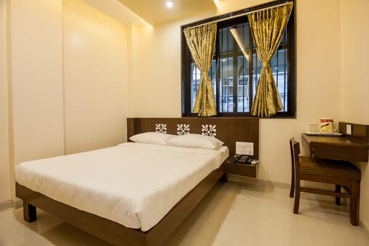 A bedroom with a bed, a desk, and a chair.