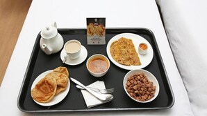 Una bandeja con tetera, taza, plato de pan plano, tazón de sopa, plato de pan plano, tazón de maní y un menú.