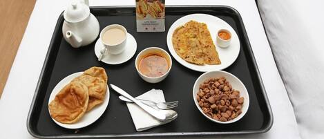 A tray with a teapot, cup, plate of flatbread, bowl of soup, plate of flatbread, bowl of peanuts, and a menu.