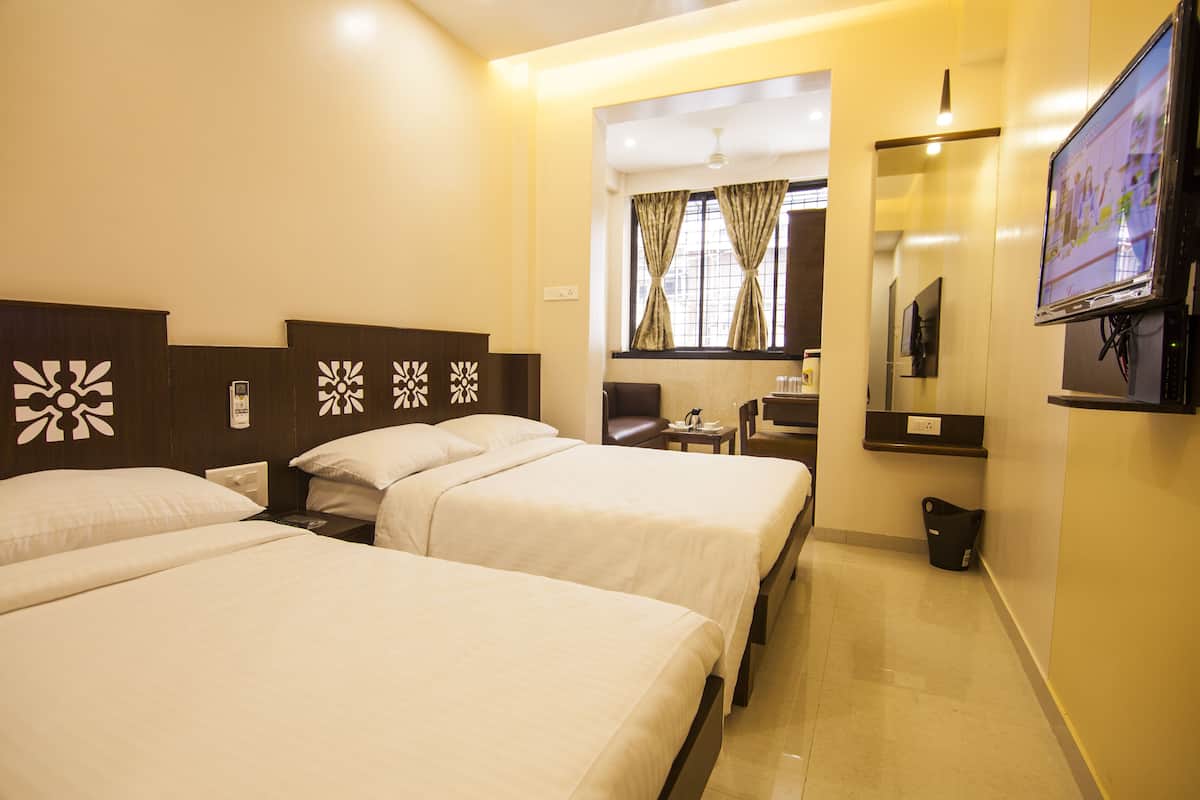 A hotel room with two beds, a TV, a small table, and a trash bin.
