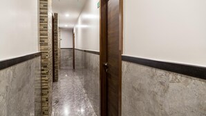 Un pasillo con piso de mármol, puerta de madera y pared decorativa de ladrillo.