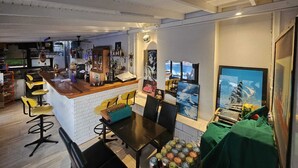 A dining area with a bar, wooden chairs, a black table, and a green tablecloth. - Nil Hotel (Ayvalik)
