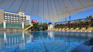A swimming pool with clear blue water, a yellow slide, and lounge chairs along the edge. - Nil Hotel (Ayvalik)