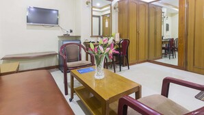 Habitación de hotel con una mesa de comedor de madera, un televisor montado en la pared, un espejo y un armario.