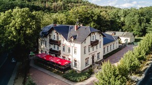 A traditional European hotel with multiple stories, a central courtyard, and a restaurant with red umbrellas. - Historische Spitzgrundmühle Coswig (Coswig)