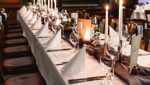 A long dining table set with candles, glasses, and a menu stand. - Historische Spitzgrundmühle Coswig (Coswig)
