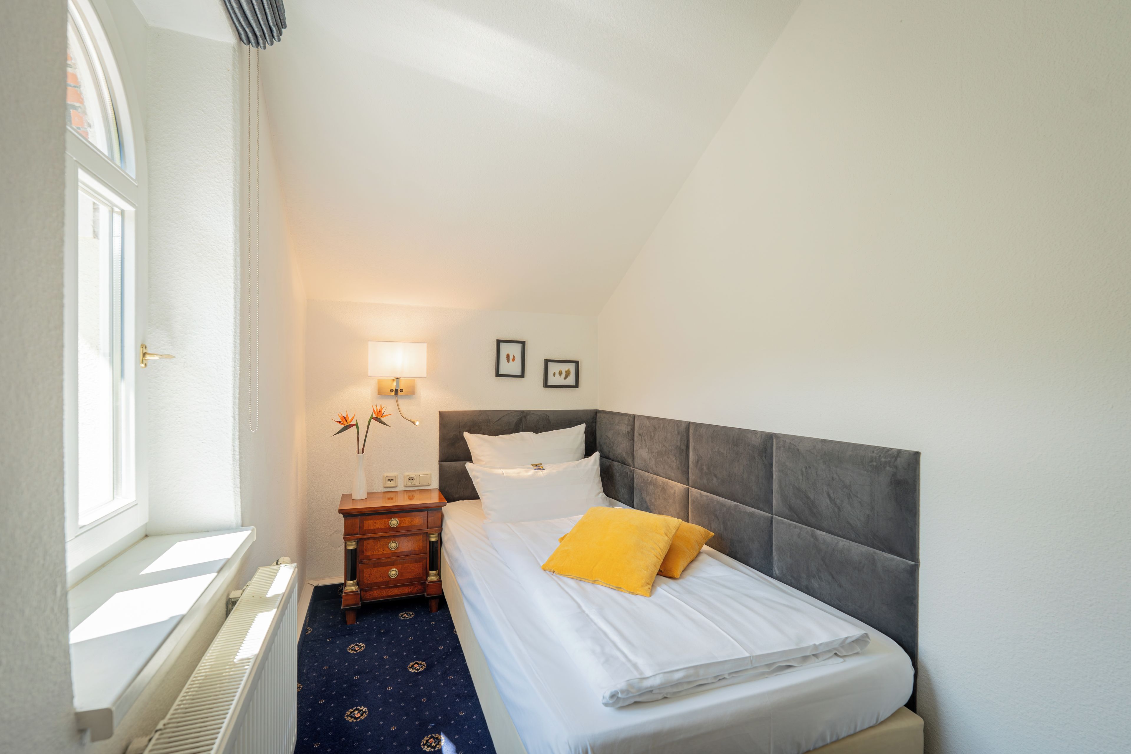 Una habitación de hotel con cama, mesita de noche, lámpara y ventana.