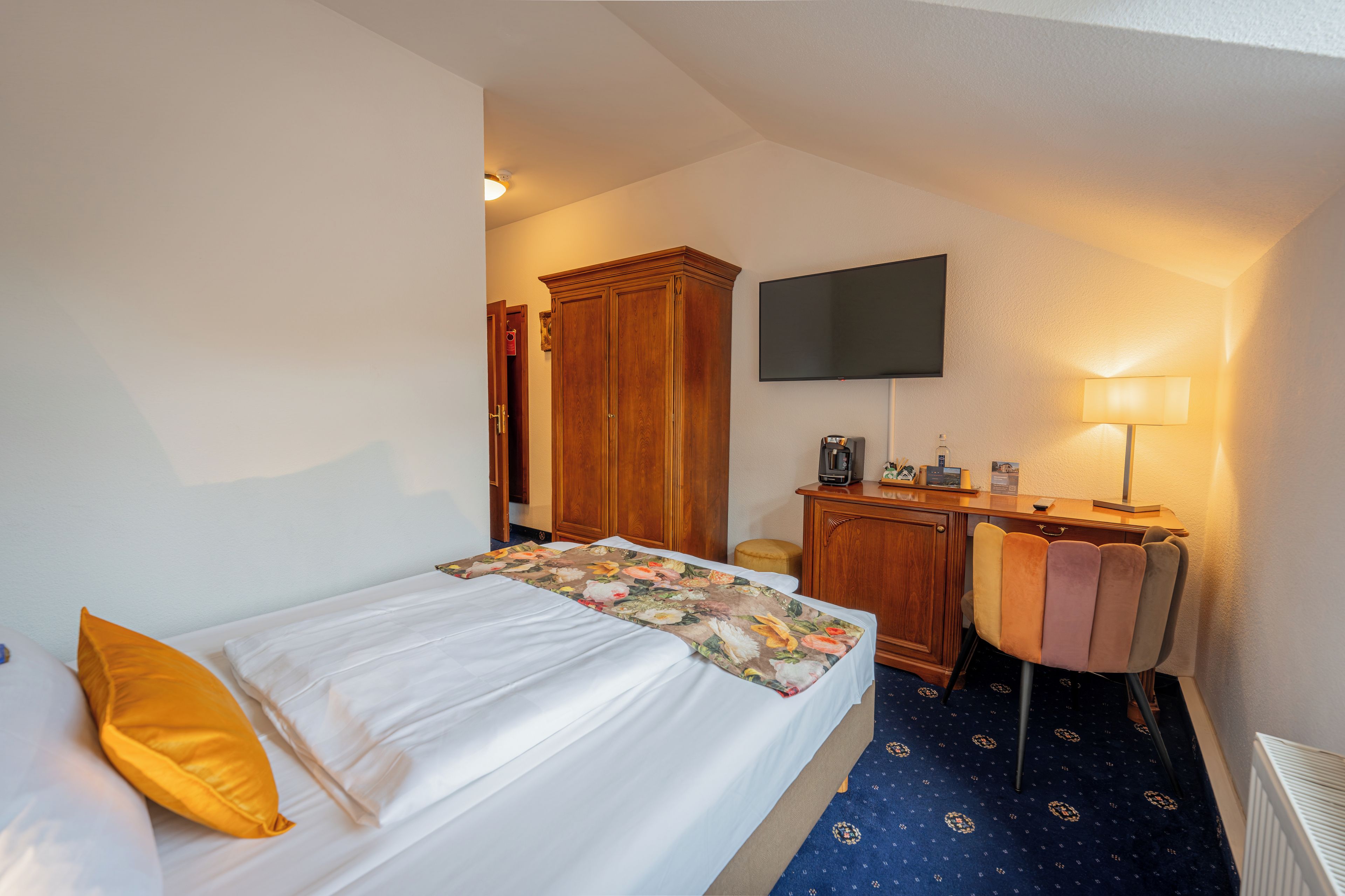Une chambre d’hôtel équipée d’un lit, d’un bureau, d’une chaise, d’une télévision et d’une lampe.