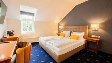 Une chambre d’hôtel avec un lit double, un bureau, une chaise, une fenêtre et un tapis à motifs.