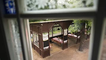 Een overdekt terras met tafels en stoelen, een houten omheining en een bord met de naam van een biermerk.