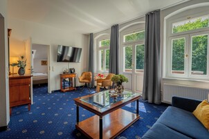 A hotel room with a large window, a flat-screen TV, a sofa, a coffee table, and a bed.