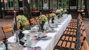 A long dining table set with white tablecloths, wooden chairs, and floral centerpieces. - Historische Spitzgrundmühle Coswig (Coswig)