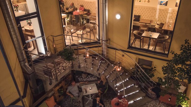 A multi-level indoor space with a central staircase, seating areas, and tables. - Hotel Rathaus Wein & Design (Vienna)
