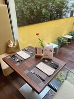 Uma mesa de jantar posta com um jogo de toalha, guardanapos, talheres e suporte para cardápio.