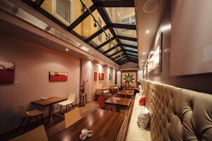 Um restaurante moderno com mesas e cadeiras de madeira, teto alto com claraboias e um espaço acolhedor com bancos estofados.