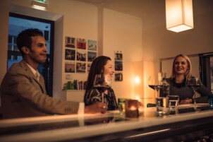 Een bar met een toonbank, glazen en een persoon in pak.